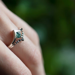 Sterling silver black diamond chevron band and sterling silver green moissanite chevron ring on hand
