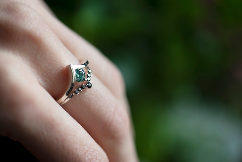 Sterling silver black diamond chevron band and sterling silver green moissanite chevron ring on hand