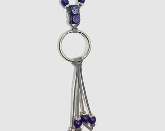 Peut inclure: Un collier composé de perles sphériques violettes avec des entretoises argentées, un anneau métallique argenté central et quatre cordons en cuir gris, chacun terminé par une perle violette unique avec des détails argentés.