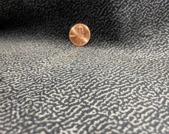 May include: Close-up of a black fabric with a white, abstract, organic pattern. A penny is placed on the fabric for scale.