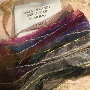 May include: A grab bag of 16 yards of spark organdy ribbon with gold edge. The ribbon is in a variety of colors, including pink, purple, blue, and black.