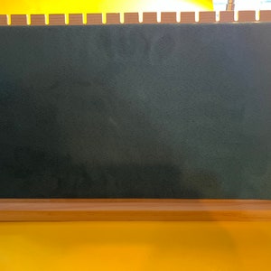 May include: A wooden display stand with a green felt surface and multiple holes for displaying jewelry or other small items.