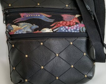 May include: Black crossbody bag with a quilted design and gold accents. The bag has two zippered compartments and a long adjustable strap. The lining features a colourful print of horses.