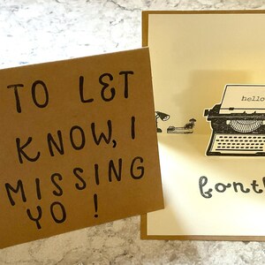 Puede incluir: Dos tarjetas de felicitaci&oacute;n. Una es marr&oacute;n con texto escrito a mano en negro: "J ST TO L&T YO KNOW, I AM MISSING YO!". La otra es una tarjeta desplegable con una ilustraci&oacute;n de m&aacute;quina de escribir y la palabra "hello" en el papel. La palabra "fontly" est&aacute; escrita debajo.