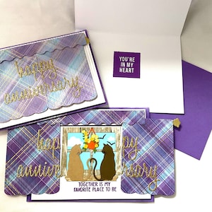 May include: Anniversary cards with a purple, blue, and gold plaid design. The cards have gold glitter script that reads "Happy Anniversary". One card features a cat silhouette scene with the text "Together is my favorite place to be."