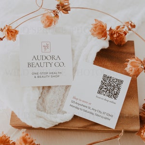 Może przedstawiać: Dwie wizyt&oacute;wki z białym tłem i brązowym tekstem. G&oacute;rna wizyt&oacute;wka zawiera napis "Audora Beauty Co. One-Stop Health & Beauty Shop". Dolna wizyt&oacute;wka zawiera kod QR i napis "Scan to shop online Shop in-store at 123 Anywhere St, Any City, ST 12345 Monday to Saturday, 11AM to 6PM"