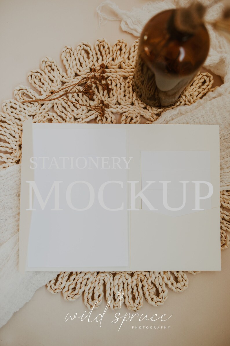 Puede incluir: Una tarjeta blanca con el texto "STATIONERY MOCKUP" sobre un fondo beige. La tarjeta est&aacute; rodeada de una estera de paja tejida y una botella de vidrio marr&oacute;n con flores secas.