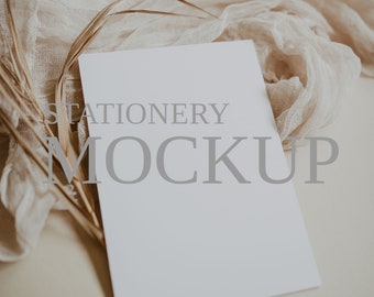 Puede incluir: Una tarjeta blanca con el texto "STATIONERY MOCKUP" sobre ella, que se encuentra sobre una superficie beige con un trozo de tela beige y hierba seca.