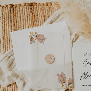 May include: A white wedding invitation with a pink floral design and a wax seal. The invitation reads "Welcome to the wedding of Carly and Alex. Let's celebrate!"