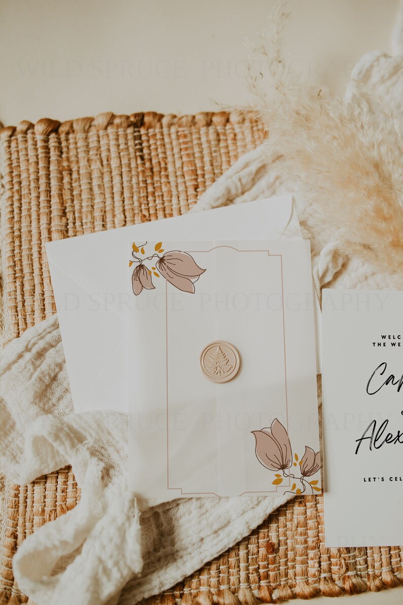 May include: A white wedding invitation with a pink floral design and a wax seal. The invitation reads "Welcome to the wedding of Carly and Alex. Let's celebrate!"