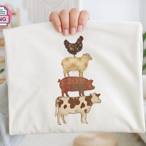 May include: Cream-coloured fabric with a patchwork design of farm animals stacked. A cow, pig, sheep, and chicken are depicted, each with unique patterns and colours. The design is centrally placed on the fabric.