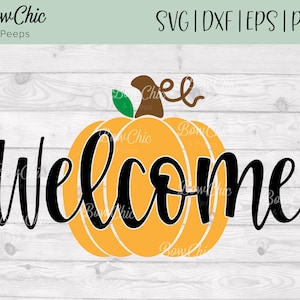 May include: A black and white welcome sign with a stylized pumpkin in the center. The pumpkin is orange with a green stem and brown swirl on top. The background is a white woodgrain pattern.