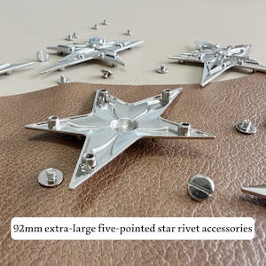 May include: Silver-toned metal five-pointed star rivet accessories measuring 92mm. The set includes multiple star-shaped pieces with threaded backings and small circular screw components, designed for attachment to leather or fabric materials.
