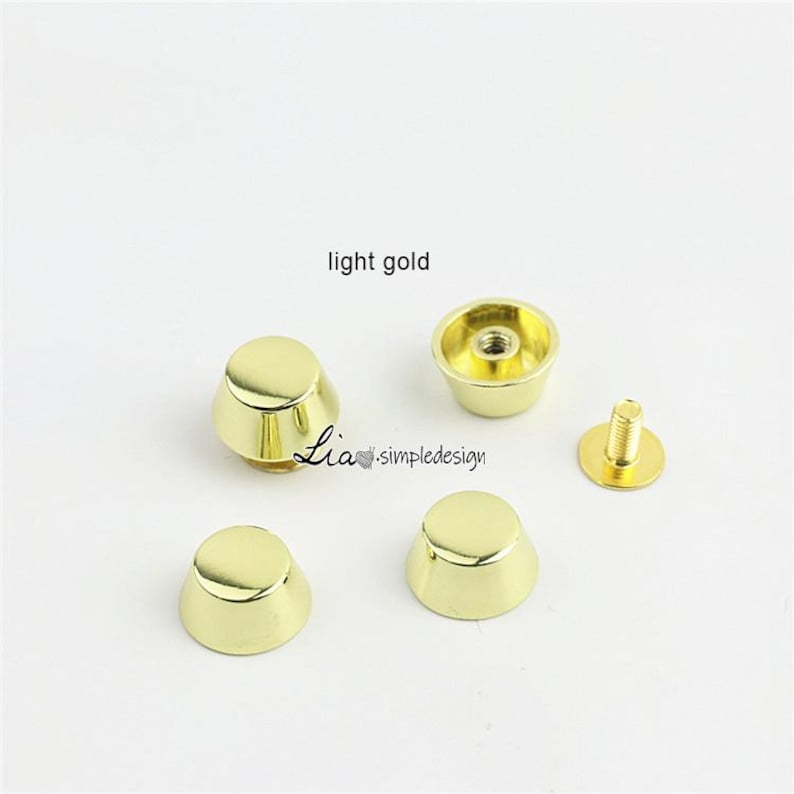 May include: Light gold metal bag feet and screw-back studs. The image shows four cone-shaped feet, one screw-back stud, and a cup-shaped stud. The text "light gold" is visible in the image. The brand name "Lia simpledesign" is also visible.