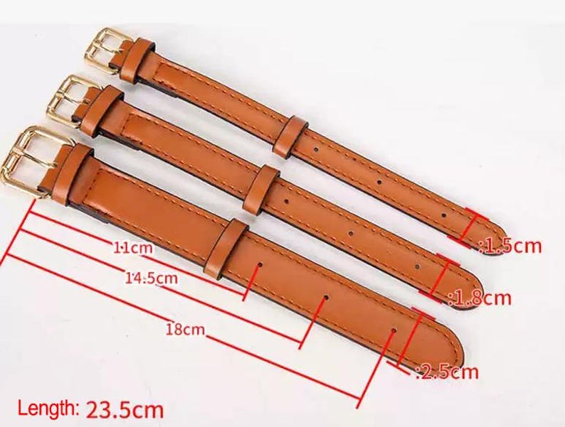 May include: Three tan watch straps with gold-tone metal buckles. The straps have varying widths of 1.5 cm, 1.8 cm, and 2.5 cm. The total length of the straps is 23.5 cm, with adjustment hole positions marked at 11 cm, 14.5 cm, and 18 cm.
