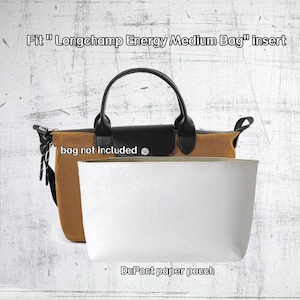 May include: A tan and black handbag with a black handle and a white pouch. The text "Fit Longchamp Energy Medium Bag insert" is at the top. The text "bag not included" is on the bag. The text "DuPont paper pouch" is at the bottom.