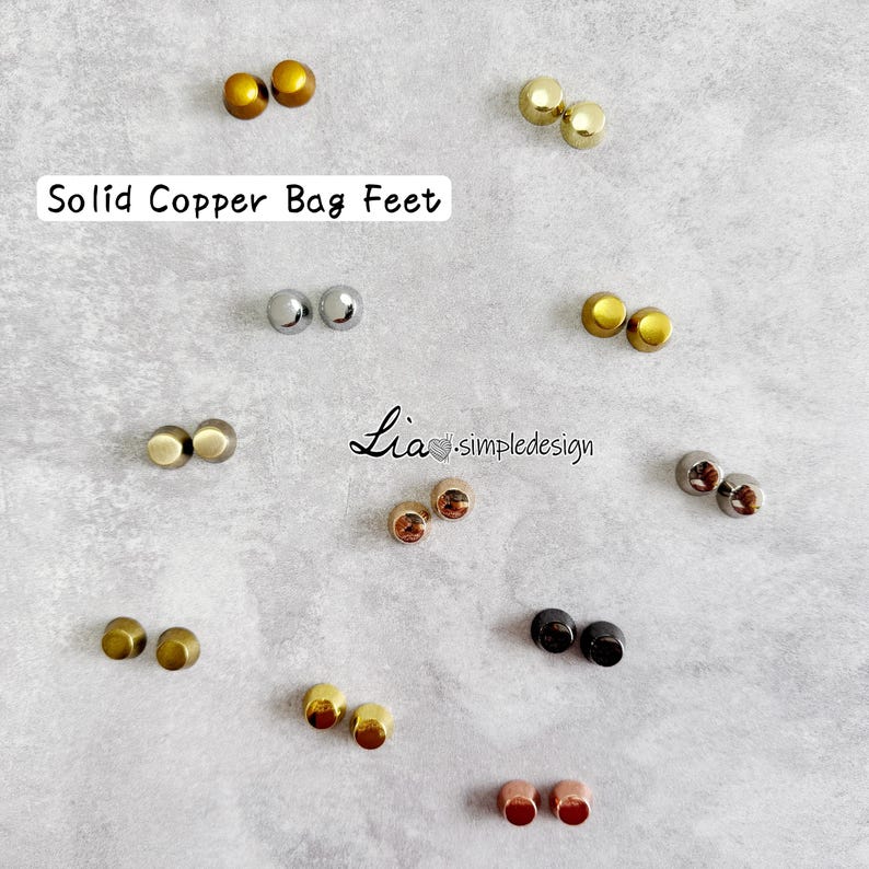 May include: A selection of solid copper bag feet in different metallic finishes, such as gold, silver, and bronze. The image displays several pairs of the small, rounded feet, suitable for attaching to the base of bags. Text on the image reads "Solid Copper Bag Feet".