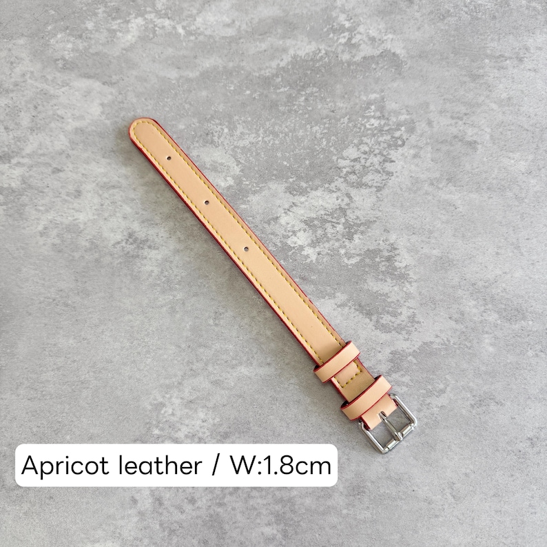 May include: An apricot leather watch strap featuring a silver-toned metal buckle, two matching leather keepers, and visible stitching along the edges. The strap includes a series of punched holes for adjustment and measures 1.8 cm in width.