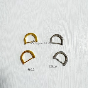 May include: Two D-shaped metal rings, one gold and one silver. The rings are about 1 inch in diameter.