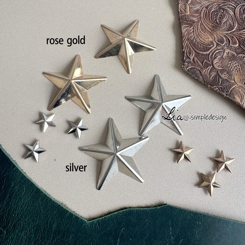 May include: A close-up of two sets of star-shaped metal embellishments. The larger stars are available in rose gold and silver. The smaller stars are silver and are scattered around the larger stars. The text "rose gold" and "silver" are written on the image.