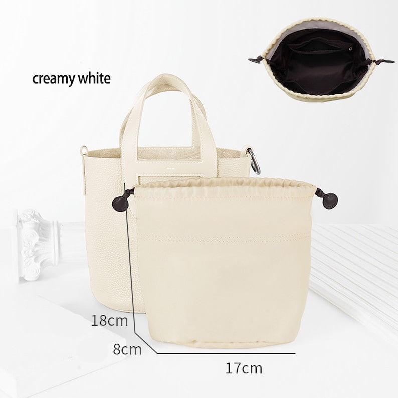 May include: Creamy white leather tote bag with a top handle and a detachable shoulder strap. The bag measures 18 cm tall, 8 cm wide, and 17 cm in diameter.