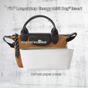 May include: A brown and black handbag with a black handle and a white insert. The insert is labeled "DuPont paper pouch". The text "Fit Longchamp Energy MINI Bag insert" is at the top. The text "bag not included" is on the bag.