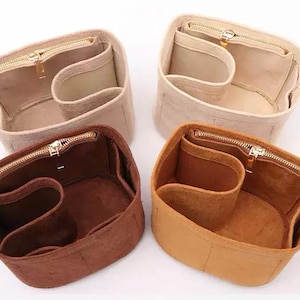 Peut inclure: Quatre organiseurs de sac en feutre avec fermetures à glissière. Deux sont beiges, un est brun et un est brun foncé.