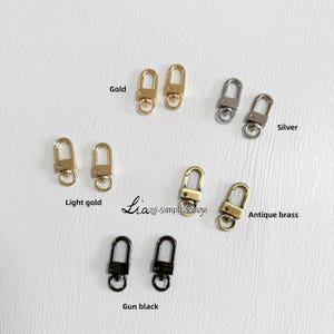 May include: A set of six pairs of metal swivel clasps in various finishes: gold, light gold, silver, antique brass, and gun black. Each clasp has a spring-loaded gate and a D-ring.