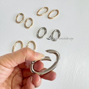 May include: Assortment of oval-shaped metal rings in gold and silver tones. The rings are approximately 1 inch in diameter.  Lia Simpledesign is written on the white surface.