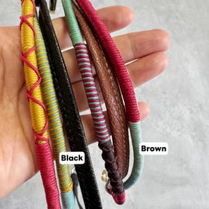 May include: Close-up of several colorful straps. The straps are in various colors, including yellow, red, black, brown, and teal. The black strap has a smooth texture, while the brown strap has a textured surface. The straps are labeled "Black" and "Brown".