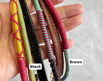 May include: Close-up of several colorful straps. The straps are in various colors, including yellow, red, black, brown, and teal. The black strap has a smooth texture, while the brown strap has a textured surface. The straps are labeled "Black" and "Brown".