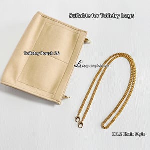 May include: A beige toiletry pouch with the text "Toiletry Pouch 26" and a gold chain. The pouch is rectangular with a pocket and zipper closures. The gold chain is labelled "NO.2 Chain Style". The text "Suitable for Toiletry bags" is also visible.