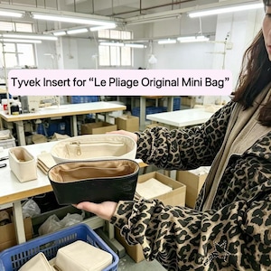 May include: Three Tyvek inserts for "Le Pliage Original Mini Bag" in cream, black, and beige. The cream-colored insert has a zipper. The black insert is made of leather. The inserts are displayed in a workshop setting.