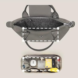 May include: A gray handbag with a top zipper and two handles is shown from above. Below it, a gray organizer with multiple compartments holds various items, including a white case, perfume bottle, and yellow packet.