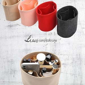 May include: Four felt bag organizers in beige, pink, red, and gray. The beige organizer is filled with various items, including a cell phone, makeup, and a small bottle of perfume. The text "Lia.simpledesigns" is visible in the image.
