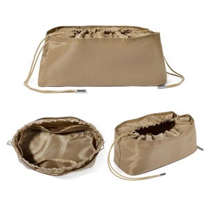 Può includere: Una borsa organizer rettangolare color beige con chiusura a coulisse. La borsa ha una texture liscia e leggermente lucida e presenta diversi scomparti interni. I cordini sono di colore beige chiaro e hanno punte metalliche argentate.