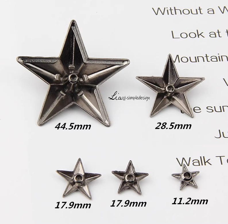 May include: Five silver metal star-shaped embellishments in various sizes. The largest star measures 44.5 mm, the next largest measures 28.5 mm, and the three smallest stars measure 17.9 mm and 11.2 mm.