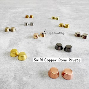 May include: A selection of solid copper dome rivets in gold, silver, and copper finishes. The rivets are displayed on a light grey surface. Text reads "Solid Copper Dome Rivets".