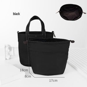 May include: Black leather tote bag with a top handle and a drawstring pouch. The bag measures 18 inches tall, 8 inches wide, and 17 inches deep.