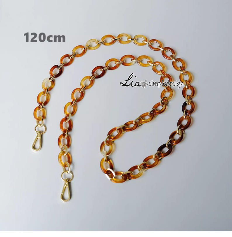 Pode incluir: Uma corrente marrom e dourada com dois fechos. A corrente tem 120 cm de comprimento.