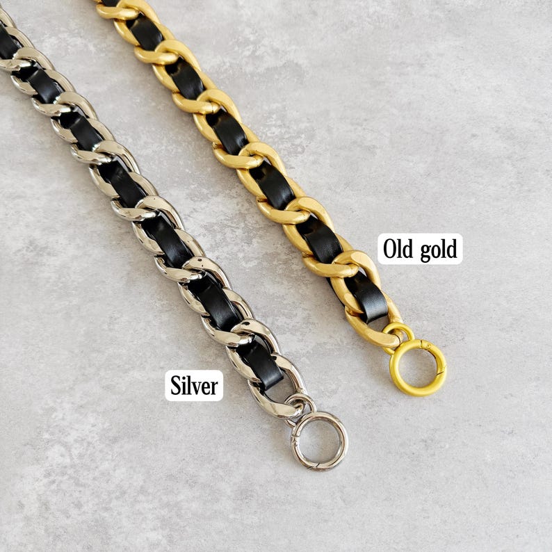 Peut inclure: Deux cha&icirc;nes m&eacute;talliques avec du cuir noir entrelac&eacute; dans les maillons. Une cha&icirc;ne est argent&eacute;e et porte l'&eacute;tiquette Silver, tandis que l'autre est dor&eacute;e et porte l'&eacute;tiquette Old gold. Chaque sangle poss&egrave;de un anneau m&eacute;tallique circulaire.