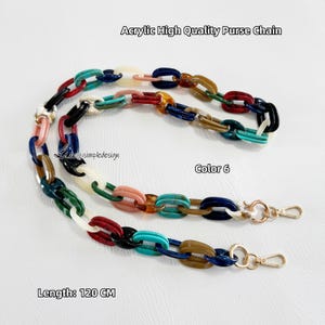 May include: A 120 cm long acrylic purse chain featuring multicolored oval links in shades of red, blue, green, black, white, and brown. The chain includes gold-tone metal lobster claw clasps at both ends. Text reads Acrylic High Quality Purse Chain, Color 6, and Length: 120 CM.