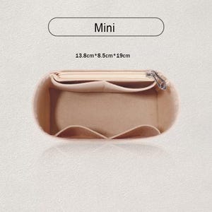 Pode incluir: Organizador de bolsa em feltro bege com vários compartimentos e zíper superior. O organizador é rotulado como "Mini" e mede 13,8 cm x 8,5 cm x 19 cm.