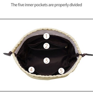 May include: A beige drawstring bag with a brown lining. The bag has five inner pockets, numbered 1 through 5.