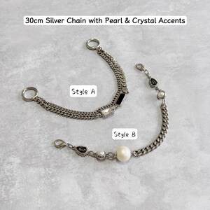 May include: Two silver chains with pearl and crystal accents. Style A is a 30cm chain with black and crystal accents. Style B is a 30cm chain with a large pearl and crystal accents. The text on the image reads "30cm Silver Chain with Pearl & Crystal Accents", "Style A", and "Style B".