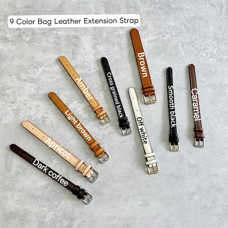 May include: A collection of nine leather bag extension straps in various colors including dark coffee, apricot, light brown, amber, cross grained black, off white, brown, smooth black, and caramel, each featuring a metal buckle and strap loop.