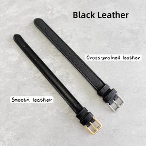 May include: Two black leather watch straps. One strap features a smooth texture with a gold-tone buckle, while the other has a cross-grained texture with a silver-tone buckle. Both straps include multiple adjustment holes and two leather keepers.