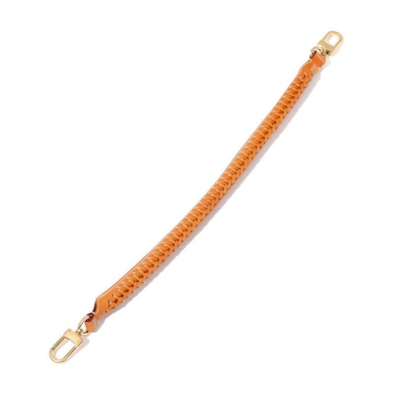 May include: A tan leather bag strap with a woven design. The strap has gold-coloured metal clasps on each end. The strap is curved and appears to be new.