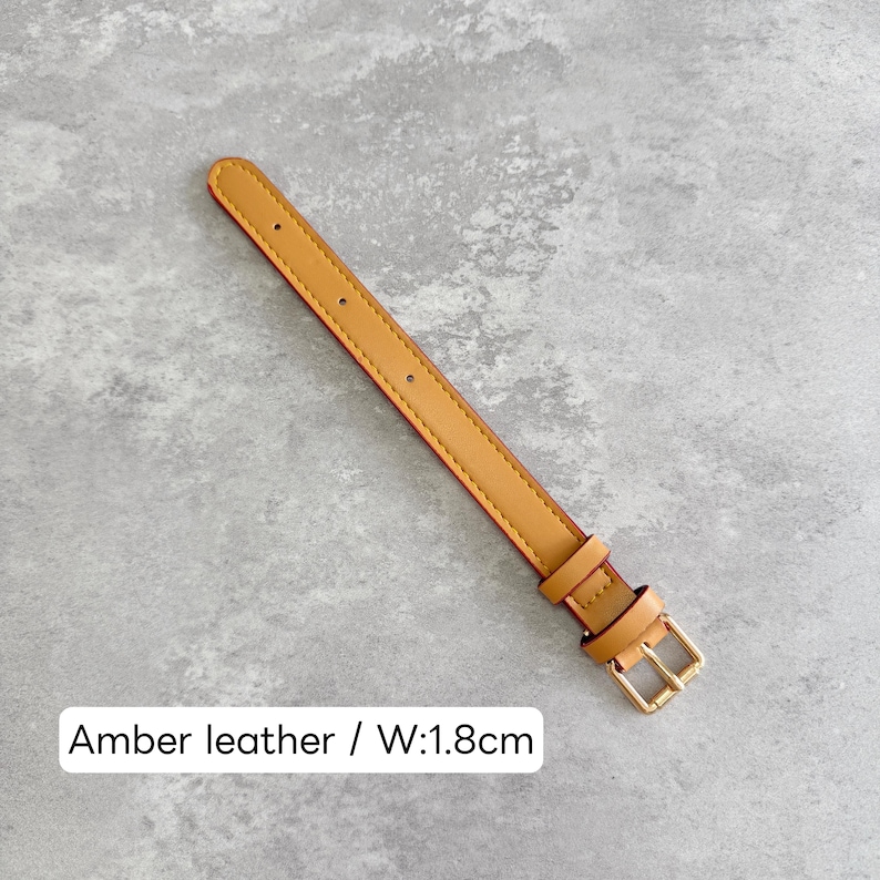 May include: An amber leather watch strap featuring a gold-toned metal buckle and two matching keepers. The strap has a series of pre-punched holes for adjustment and a width of 1.8 cm as indicated by the text label in the image.