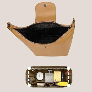 May include: A tan leather handbag with a top flap and zipper closure. The interior is black. Below the handbag is a green organizer with various items, including a white container, a perfume bottle, and a yellow box.